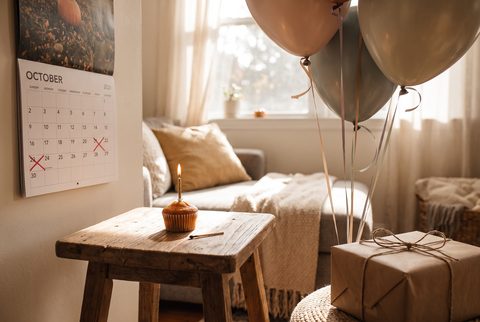 Cozy room with an October calendar with crossed-off days, a cupcake with a candle, balloons and a wrapped gift
